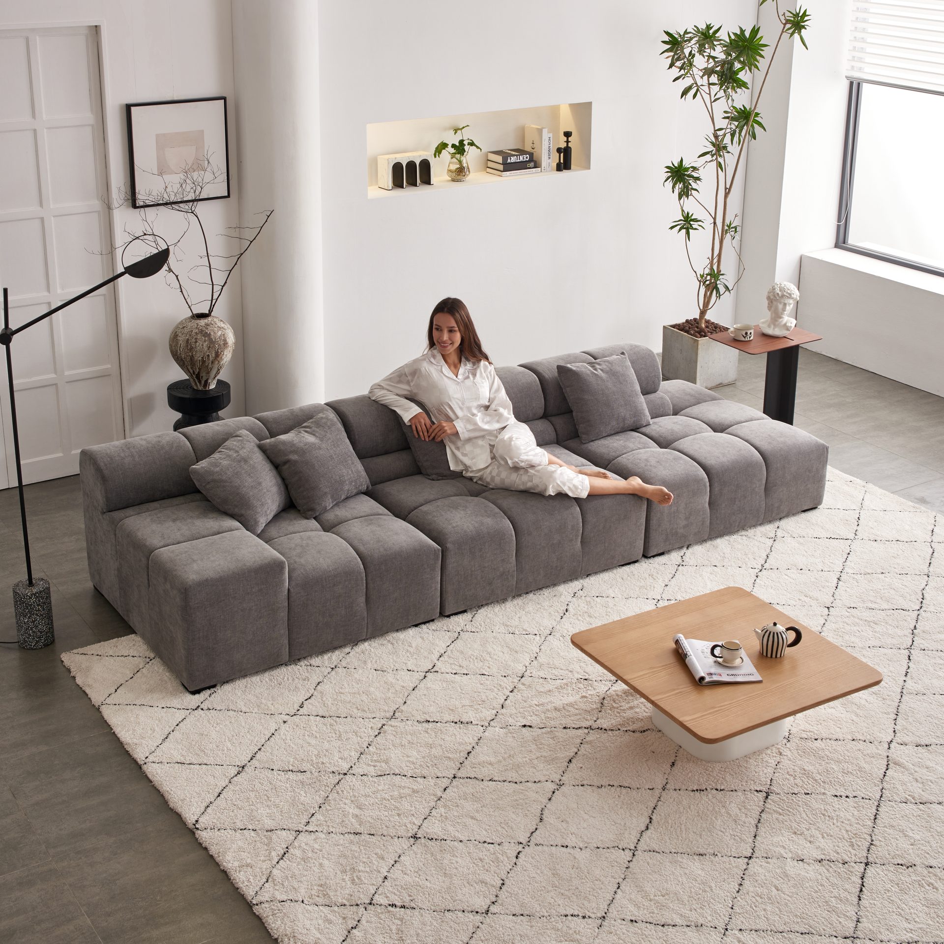 Woman reclining on the charcoal grey Amora modular sectional sofa