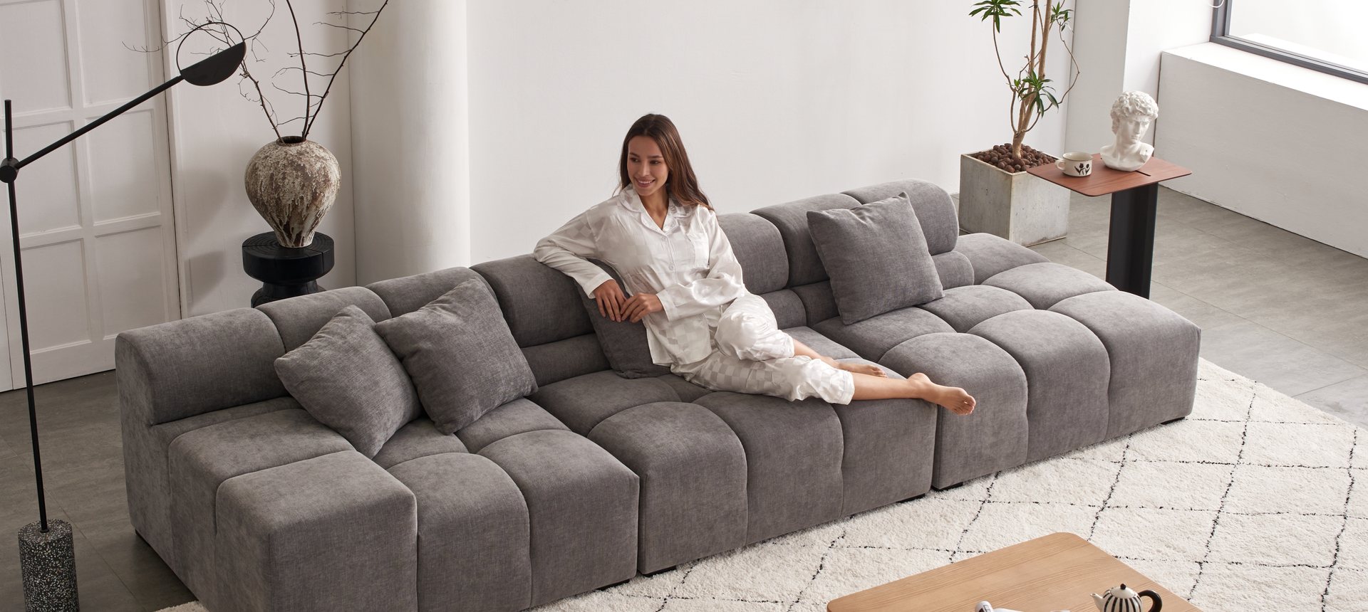 Woman relaxing on the charcoal grey Amora modular sectional sofa
